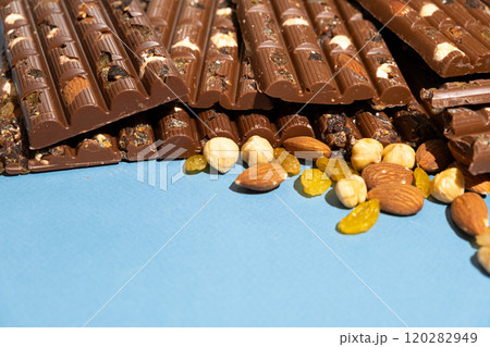 Lots of chocolate bars with nuts and raisins on a blue background space for text Lots of chocolate bars with nuts and raisins on a blue background space for text 120282949