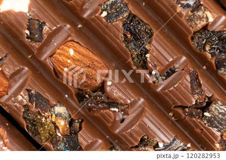 Macro background of milk nut chocolate with raisins. 120282953