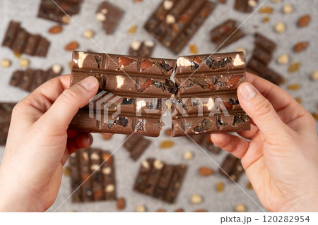 Broken chocolate bar in hands close-up view from above. 120282954