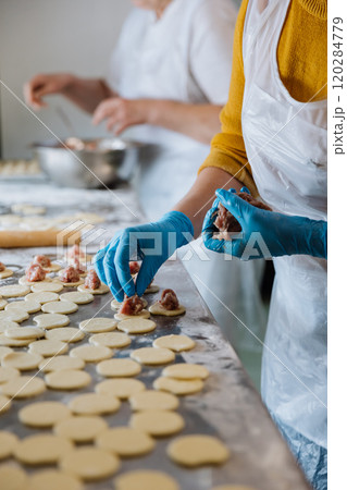 Making homemade dumplings, placing meat filling on dough circles in a busy kitchen environment Making homemade dumplings, placing meat filling on dough circles in a busy kitchen environment 120284779