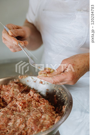 Filling a handmade dumpling with minced meat using a fork, traditional cooking process close up Filling a handmade dumpling with minced meat using a fork, traditional cooking process close up 120284783