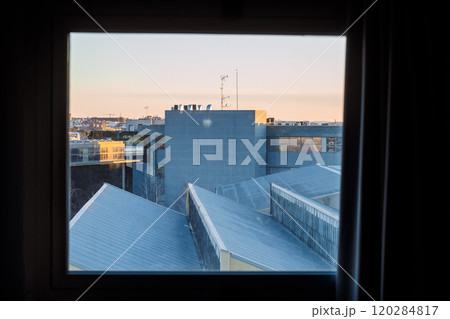 Framed view of modern building rooftops with antennas and urban skyline during sunset 120284817