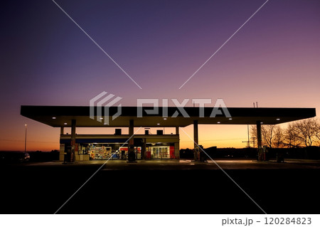 Illuminated gas station under a darkening twilight sky with empty surroundings and no visible vehicles or people 120284823