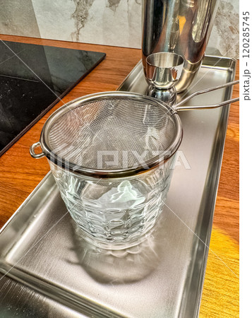 a small metal strainer on a glass of ice for making cocktail . High quality photo 120285745