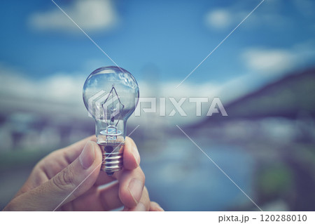 電球を持つ人の手元とぼかし風景 120288010