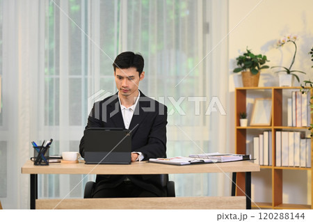 Focused entrepreneur in black suit working on digital tablet in modern office Focused entrepreneur in black suit working on digital tablet in modern office 120288144