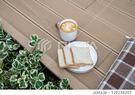 Plate of toast and a cup of coffee on a wooden terrace Plate of toast and a cup of coffee on a wooden terrace 120288202