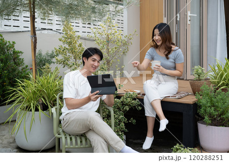 Relaxed millennial couple enjoying morning conversation and beverages in the backyard Relaxed millennial couple enjoying morning conversation and beverages in the backyard 120288251