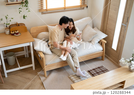 Happy millennial Asian couple using a smart phone together on sofa at home Happy millennial Asian couple using a smart phone together on sofa at home 120288344