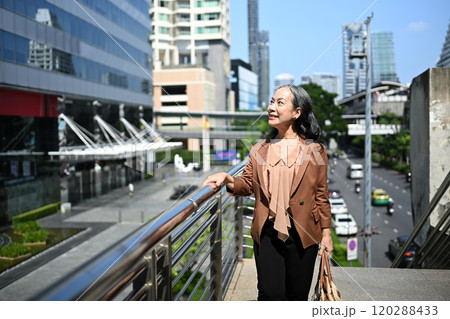 Elegant mature businesswoman enjoying a sunny day in the urban landscape Elegant mature businesswoman enjoying a sunny day in the urban landscape 120288433