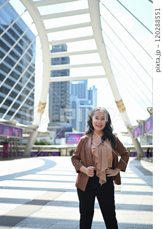 Elegant middle aged businesswoman in stylish suit standing confidently in the city center Elegant middle aged businesswoman in stylish suit standing confidently in the city center 120288551