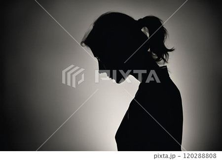 暗い部屋でうつむいている女性の横顔のシルエット 暗い部屋でうつむいている女性の横顔のシルエット 120288808