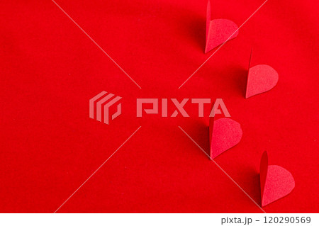 Hand cut paper hearts on a red background Hand cut paper hearts on a red background 120290569