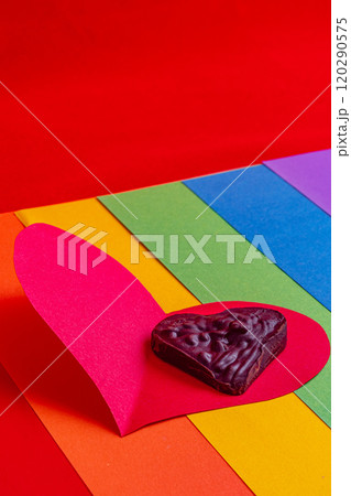lgbt concept, chocolate heart on paper red on rainbow flag on red background lgbt concept, chocolate heart on paper red on rainbow flag on red background 120290575