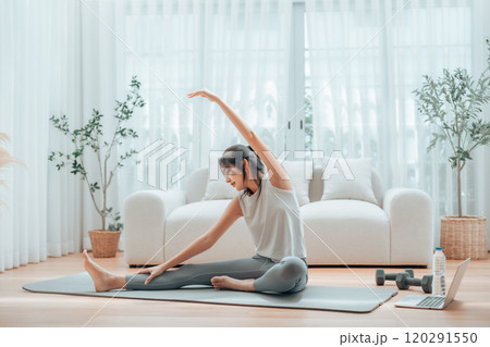 Happy young Asian woman practicing yoga and shoulder stretching at home Happy young Asian woman practicing yoga and shoulder stretching at home 120291550