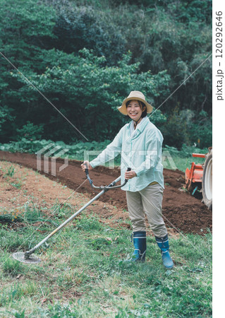 畑周りの雑草を刈払機で刈る女性 畑周りの雑草を刈払機で刈る女性 120292646