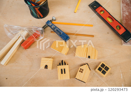 Wooden houses, pencils, and tools on a workbench. Perfect for home construction, DIY projects, and handmade woodwork. Carpentry tools for crafting at home workshop 120293473