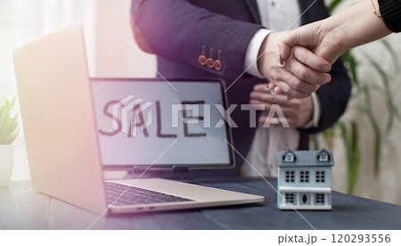 Handshake Agreement in Real Estate Sale with Laptop and Model House on Desk 120293556