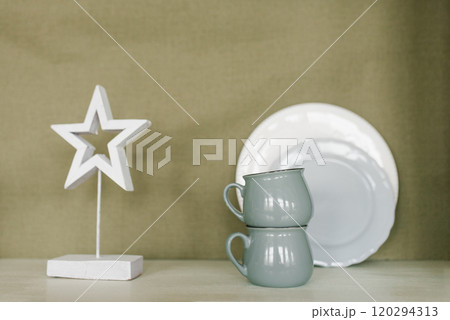 White star is on a shelf next to two cups and a white plate 120294313