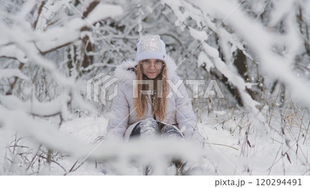 Portrait of a teenage girl sitting in a snowy fairy forest and throwing snow. Portrait of a teenage girl sitting in a snowy fairy forest and throwing snow. 120294491