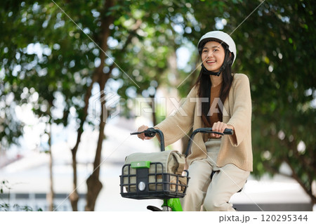 A woman is riding a bicycle with a basket on the front A woman is riding a bicycle with a basket on the front 120295344