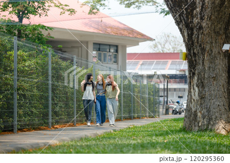 Three women walking down a sidewalk in front of a building Three women walking down a sidewalk in front of a building 120295360