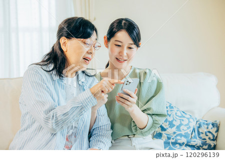 スマホを見ながら仲良く会話をする親子 スマホを見ながら仲良く会話をする親子 120296139