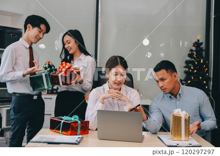 full length view of a group of business team wearing red Santa hat and exchange gift box together in the office for Christmas. full length view of a group of business team wearing red Santa hat and exchange gift box together in the office for Christmas. 120297297
