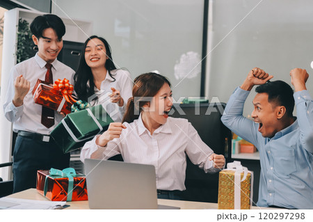 full length view of a group of business team wearing red Santa hat and exchange gift box together in the office for Christmas. 120297298
