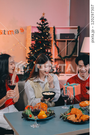 Friends opening Christmas gifts in living room 120297307