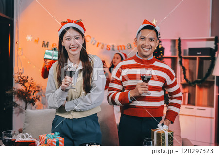 Group of happy Asian friends celebrating Christmas and decorate the Christmas tree indoors. Beauty woman with Christmas Gifts. New Year party. Woman hands decorate Christmas tree red ball, bauble. 120297323