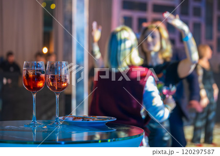 Two glasses of wine at a lively party setting Two glasses of wine at a lively party setting 120297587