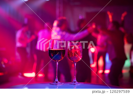 Two wine glasses on table at vibrant dance party Two wine glasses on table at vibrant dance party 120297589