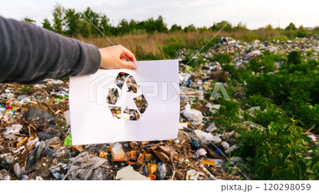 Abstract recycling concept featuring a hand holding a recycling logo icon against a garbage background. Symbolizes waste management, eco-friendly practices Abstract recycling concept featuring a hand holding a recycling logo icon against a garbage background. Symbolizes waste management, eco-friendly practices 120298059