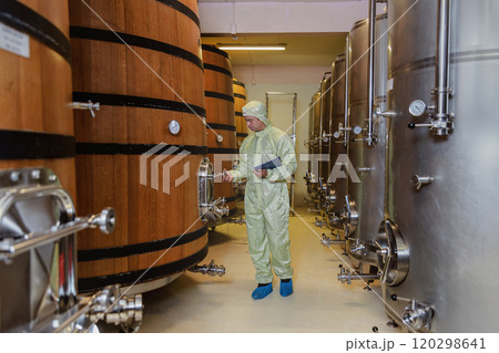 Winemaker working in modern large winery factory liquor drink industry quality. Staff inspecting wine in modern wine factory. Winery manufacturing quality control. Alcohol and wine winemaking process 120298641