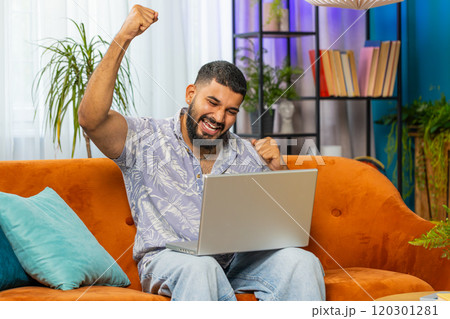 Amazed Indian man use laptop computer, receive good news message, shocked by victory, celebrate win 120301281