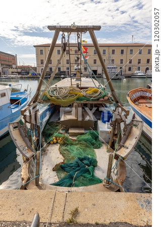 View of a fishing boat with nets and equipment docked in Livorno harbor on a sunny day 120302057