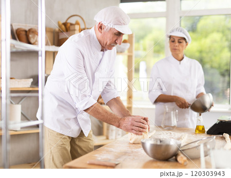Elderly male chef and female skillfully kneads dough to bake delicious bread and croissants 120303943