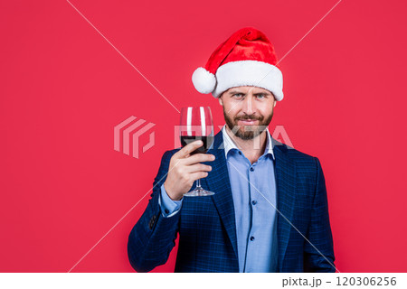 mature bearded man in santa claus hat celebrate new year party with wine glass, copy space, cheers. 120306256