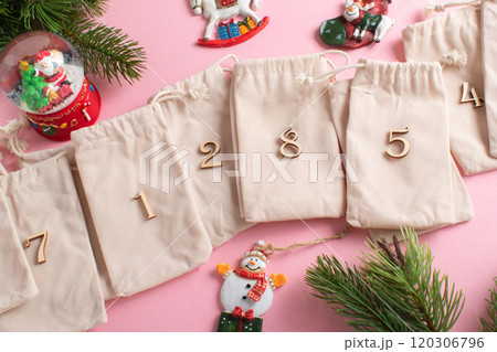 Christmas Advent calendar with gift velvet bags on a light pink background. 120306796