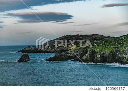 A view of a rocky coastline with a blue ocean. The water has a deep blue colour. The sky is clear and blue. The rocks are rugged and weathered. A view of a rocky coastline with a blue ocean. The water has a deep blue colour. The sky is clear and blue. The rocks are rugged and weathered. 120309157