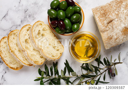 appetizer, sliced ciabatta bread, with olive oil, green olives, Chalkidiki olives, classic Green green olive, on a marble table, top view, no people, 120309387