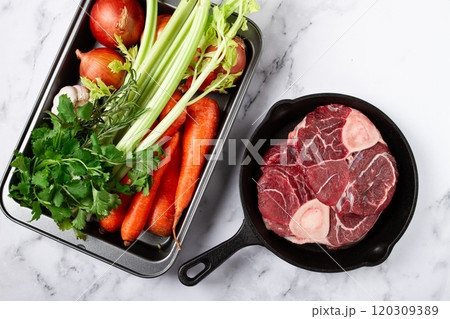 knuckle on the bone, raw meat for ossobuco, in a cast-iron pan, baking sheet with vegetables, top view, no people, 120309389