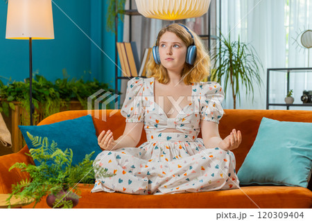 Woman breathes deeply eyes closed, meditating with concentrated thoughts, peaceful mind at home 120309404