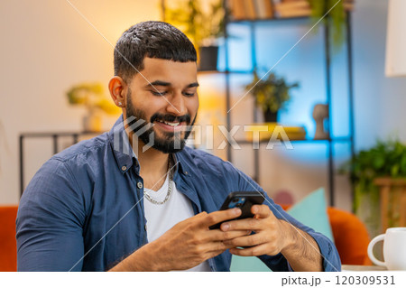Indian freelancer man using smartphone texting message while staying in workplace at home office Indian freelancer man using smartphone texting message while staying in workplace at home office 120309531