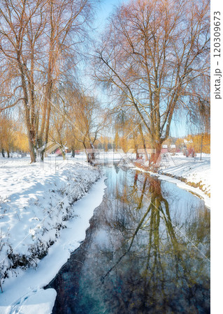 Stunning landscape with snowy trees, beautiful frozen river with reflection in water. Stunning landscape with snowy trees, beautiful frozen river with reflection in water. 120309673