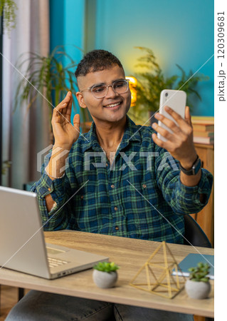 Happy Indian man taking selfie on smartphone communicating video call home online with subscribers 120309681