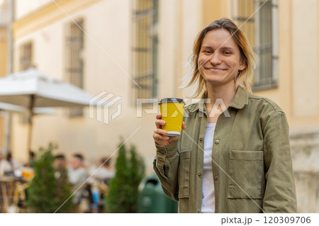 Smiling woman walking on city street enjoying morning coffee hot coffee relaxing taking a break 120309706