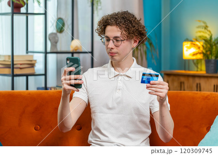 Man using credit bank card and smartphone while transferring money purchases online shopping at home 120309745