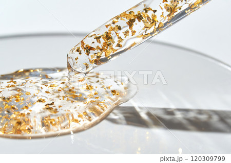 Close-up of gold-infused serum with dropper on a glass surface in sunlight 120309799